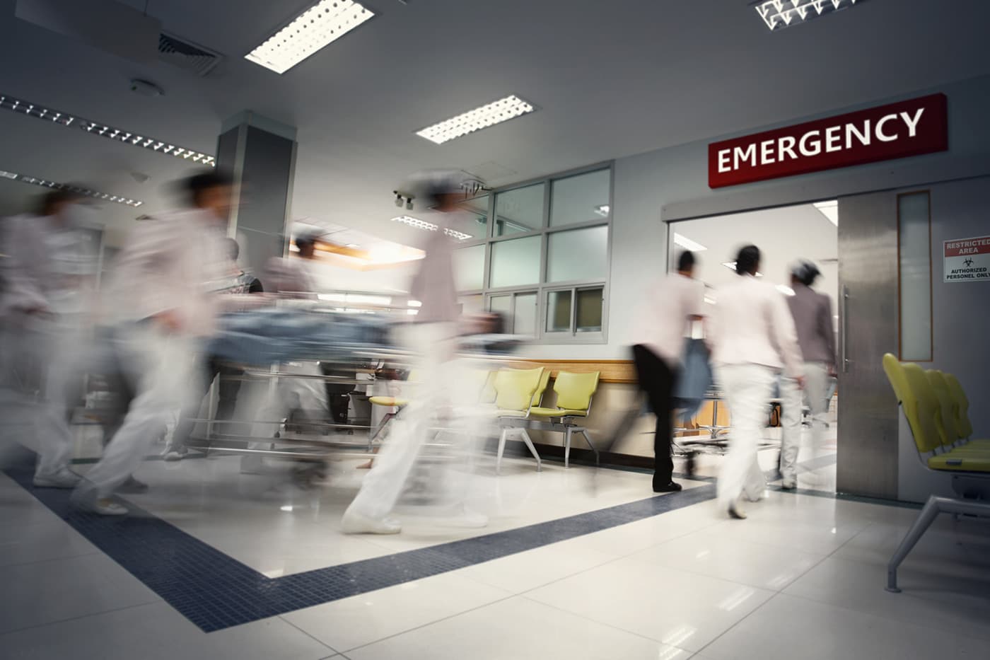 Blurred motion of medical staff moving quickly through a hospital emergency department.